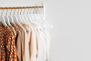 Clothing Rack with children's outfits close up. Fashion clothes in white, beige and brown colors on...