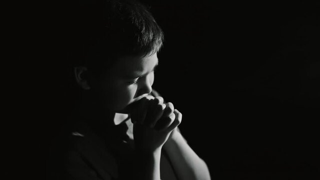 Little boy praying in the dark