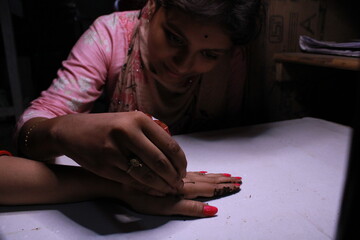 Drawing henna. Drawing mehndi tattoo on the hand of an Indian bride close up