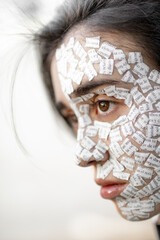 Imagen vertical de rostro con trozos de papel conceptual, foco en el ojo, bokeh en el resto, diurna 