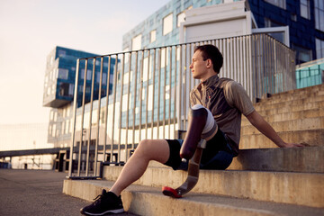 Man with a prosthetic running blade sitting on steps