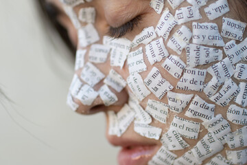 Rostro de mujer joven con trozos de papel conceptual, foco en el ojo, bokeh en el resto, diurna 