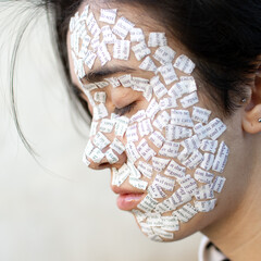 Rostro de mujer joven con trozos de papel pegados de forma simbólica, tez blanca, diurna, ojos...