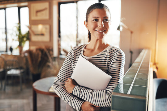 Smiling businesswoman standing with a laptop in a bright lounge