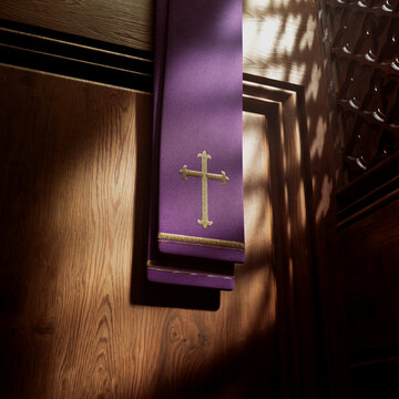 Purple liturgical stole with gold cross on wooden panel