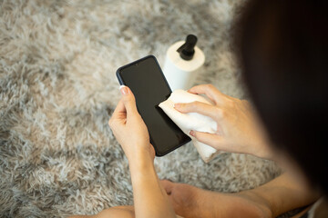 Woman hands cleaning phone screen with alchohol at home