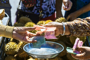 Elderly Thai female vendor ride motorcycle selling durians and fruits and vegetables to tourists at...