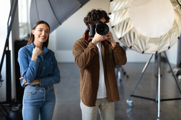 Capturing the moment. Male photographer with his trusty assistant doing photo shoot in studio
