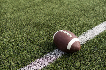 American football ball on green grass field background.