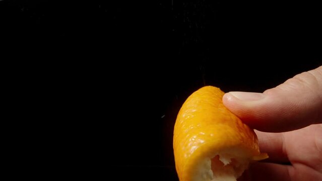 I am squeezing the orange peel against a black background, and the splashes fly in all directions, in slow motion.