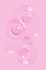 round drops of transparent gel serum on a pink background. gel with bubbles. Water droplets