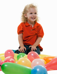 Fototapeta na wymiar Adorable little three year old boy sitting on the floor with many balloons smiling