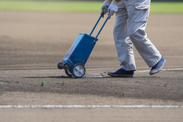 Obraz premium 野球の試合前のグランドで白線を引く整備員
