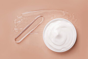 Smeared transparent gel on the background. Spatula for applying cream. A round jar of cosmetic white cream. On a beige background.