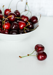 Naklejka na ściany i meble Juicy cherries on a white plate, close-up