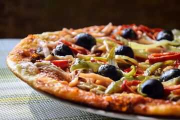 Homemade pizza. Freshly prepared Italian homemade pizza: olives, ham, pepper, sauce, cucumber, cheese. Close-up. Selective focus.