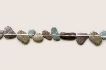 Top view still life with close-up sea stones on sand background, pebbles united by one horizontal...