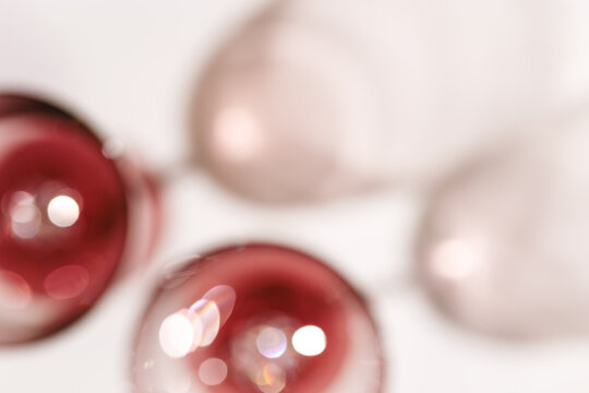 Two glasses of Red wine blurred on light white background, abstract aesthetic photo of red wine, natural light and shadow, glare and shining bokeh texture.  Holiday party concept, top view