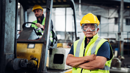 Portrait of industrial worker driving a forklift in the factory. Engineer is working and maintaining in the warehouse.