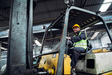Industrial worker driving a forklift in the factory. Engineer is working and maintaining in the...