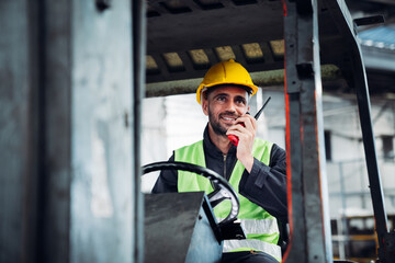 Industrial worker driving a forklift in the factory. Engineer is working and maintaining in the warehouse.