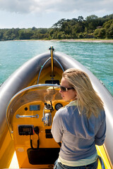 Naklejka premium A stunningly beautiful young woman driving a powerboat and having fun.