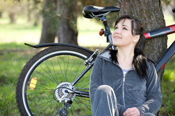 Naklejka na ściany i meble happy brunette woman relaxing in park with bike