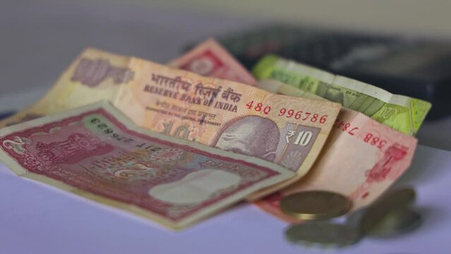 Closeup of Indian rupee coins falling over currency notes on a table
