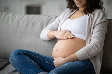 Maternity Care. Smiling Pregnant Woman Tenderly Touching Her Belly, Closeup Shot