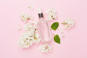 Face serum with flowers on color background, top view