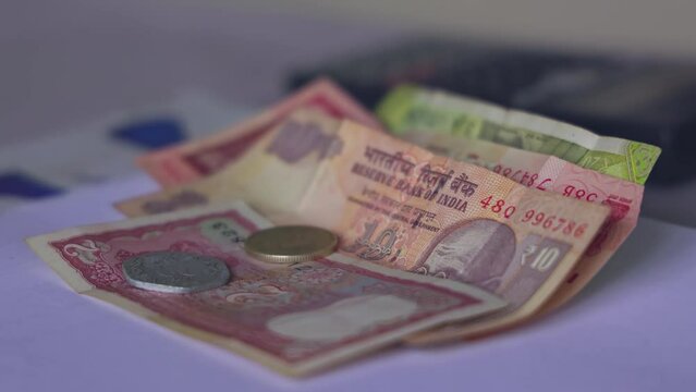 Closeup of Indian rupee coins falling over currency notes on a table