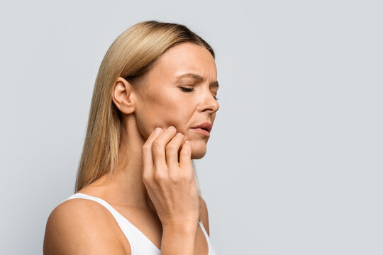 Middle aged woman in pain touching her cheek, copy space