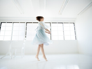 Fototapeta na wymiar 窓のある明るい室内でバレエの練習をする女性