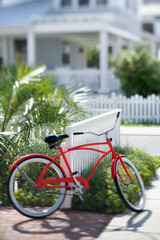 Fototapeta na wymiar Red beach cruiser bicycle propped against fence in front of house.
