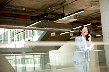 Young business woman using mobile phone in the office hallway