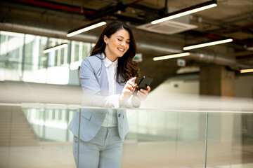 Young business woman using mobile phone in the office hallway