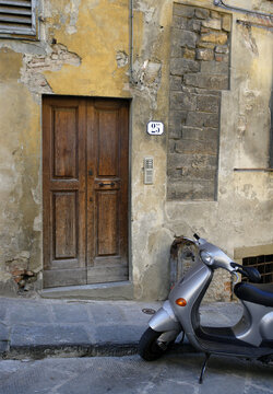 Scooter waiting outside the wooden door of a residence in Florence, Italy.