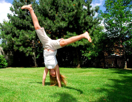 Young girl doing a cartwheel on green grass