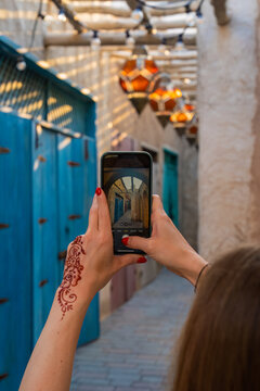 A young woman with henna on her hand takes a picture with her mobile phone in a deserted alley in Dubai Market.