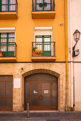 Fototapeta na wymiar Facade and main entrance of yellow building with balconies and flower pots