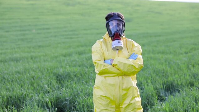 Person in overalls and gas mask call to save the planet while standing on green field on sunset