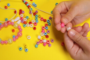 Closeup of making decorative bracelet of colored beads - obrazy, fototapety, plakaty