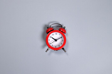 Red alarm clock on a gray background, minimalism