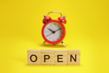 Open word and alarm clock on yellow background