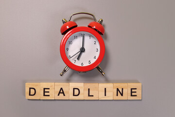 Deadline word and alarm clock on gray background