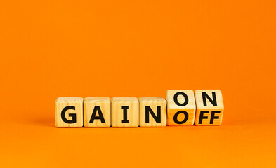 Gain on or off symbol. Businessman turns wooden cubes and changes word Gain off to Gain on. Beautiful orange table orange background. Business and gain on or off concept. Copy space.