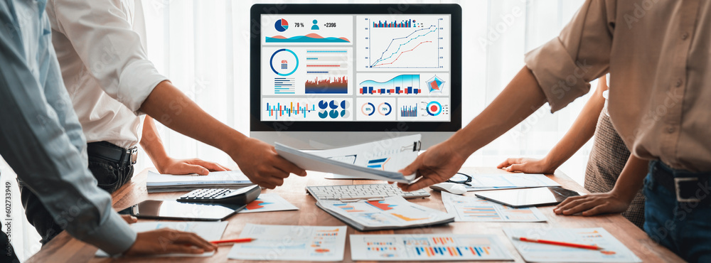 Leinwandbilder Analyst team utilizing BI Fintech to analyze and pointing at financial dashboard paper office. Businesspeople examining report paper on table for business insight. Panorama shot. Scrutinize