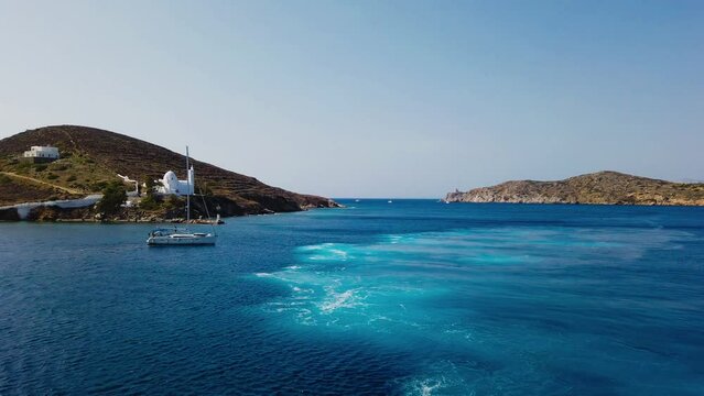 Chora, Ios Island, Greece- 26 September 2020: Boat departing from the port of Chora. Agia Irini, Saint Irene, Greek Orthodox church.