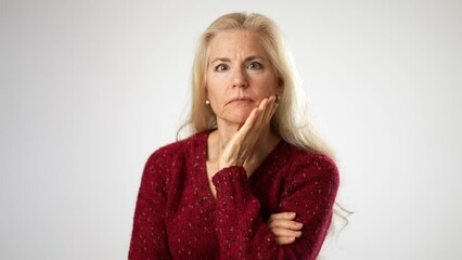 Portrait of attractive mature woman listen to secret with hand to ear, expressing doubts, unsure of heard information, suffering hearing problems at older age. Studio shot on white background
