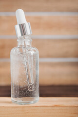 Serum or oil with dropper pipette on wood background podium close-up and copy space. Beauty skincare and healthcare concept...